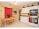 Cozy eat-in kitchen featuring white cabinets and tile flooring, complemented by natural light at 1001 57Th N Ave, St Petersburg, FL 33703