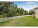 A verdant backyard bordered by a white picket fence and lush, mature trees providing privacy and a natural backdrop at 10707 Pegasus Valley Ct, Tampa, FL 33647