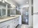 Bathroom featuring double vanity sinks, granite countertops, a large mirror, and a tiled walk-in shower at 11100 Balfour St, Venice, FL 34293