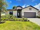 Inviting exterior with a gray garage door, stone details, and a well-kept lawn at 11100 Balfour St, Venice, FL 34293