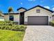 Charming home featuring a two-car garage, stone accents, lush landscaping, and inviting curb appeal at 11100 Balfour St, Venice, FL 34293