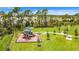 Green community playground equipped with play structures and benches, near tall trees and a walking path at 11100 Balfour St, Venice, FL 34293