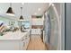 Bright kitchen features stainless steel appliances, white cabinetry and island with modern pendant lighting, and an adjacent living room at 11313 Hardwood Hammock Ln, Riverview, FL 33569