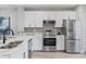 Modern white kitchen featuring stainless steel appliances, tile backsplash, and marble countertops at 11510 Shipwatch Dr # 1372, Largo, FL 33774
