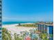 Expansive beach view with blue ocean, white sand, palm trees, and a resort-style swimming pool at 1170 Gulf Blvd # 1006, Clearwater Beach, FL 33767