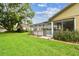 A view of the backyard with a large screened-in lanai area, with a small patch of landscaping and green grass at 12101 Meadowbrook Ln, Hudson, FL 34667