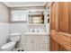 Bright bathroom with a white vanity, a large mirror, a toilet, and a wooden door at 12101 Meadowbrook Ln, Hudson, FL 34667