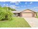 Charming home featuring a well-maintained lawn, a palm tree, and a two-car garage with brick accents at 12101 Meadowbrook Ln, Hudson, FL 34667