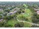 An aerial view showcases a well-manicured golf course with mature trees and cart paths at 12101 Meadowbrook Ln, Hudson, FL 34667