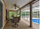 Relaxing covered patio with a ceiling fan and furniture overlooking the screened pool at 12101 Meadowbrook Ln, Hudson, FL 34667
