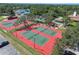 Aerial view of the red and green community tennis courts surrounded by lush trees and landscape at 12101 Meadowbrook Ln, Hudson, FL 34667