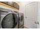 Laundry room featuring side-by-side washer and dryer with overhead storage cabinets and a nearby door at 12244 Fairlawn Dr, Riverview, FL 33579