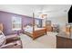 Spacious main bedroom with purple accent wall, four-poster bed, ceiling fan, and natural lighting at 12244 Fairlawn Dr, Riverview, FL 33579