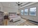 Bright main bedroom featuring tray ceilings, wood floors, large windows, and a ceiling fan at 12382 Shining Willow St, Riverview, FL 33579
