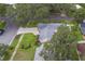 Aerial view of a home with a well-manicured lawn, complementing landscaping, and a gray roof at 1368 Whispering Pines Dr, Clearwater, FL 33764