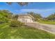 Home exterior featuring a lush green lawn, brick driveway, and manicured landscaping at 1368 Whispering Pines Dr, Clearwater, FL 33764