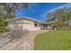 Traditional home exterior with a brick driveway, manicured lawn, and inviting front porch at 1368 Whispering Pines Dr, Clearwater, FL 33764