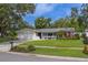Charming single-story home featuring a lush green lawn and mature trees, with a brick-paved driveway at 1368 Whispering Pines Dr, Clearwater, FL 33764
