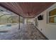 Spacious screened-in patio with a dark-stained ceiling, brick floors, a ceiling fan, and a view of the pool at 1368 Whispering Pines Dr, Clearwater, FL 33764
