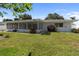 Home's exterior showcases a well-manicured lawn, lush plantings, and a screened-in porch for outdoor living at 13898 Jamaica Dr, Seminole, FL 33776
