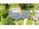 Aerial view of home, featuring a unique pool, brick patio, a driveway, and lush landscaping in the backyard at 13917 8Th St, Dade City, FL 33525