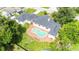 Overhead image of the home with the kidney-shaped pool, roof, green lawn, and the surrounding green trees at 13917 8Th St, Dade City, FL 33525