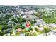 Aerial view of a home close to town and surrounded by lush greenery and neighborhood homes, marked with a red arrow at 13917 8Th St, Dade City, FL 33525