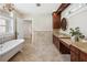 Bright bathroom featuring a soaking tub, granite countertops, dark wood cabinetry, and updated finishes at 13917 8Th St, Dade City, FL 33525