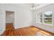 Sunlit bedroom with wood floors, white walls, ceiling fan, and view to the green yard through large windows at 13917 8Th St, Dade City, FL 33525
