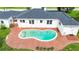 Backyard with a kidney-shaped pool with a brick surround, green lawn, and the back of the house at 13917 8Th St, Dade City, FL 33525