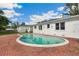 Backyard view of the in-ground pool with brick surround and the home's white exterior at 13917 8Th St, Dade City, FL 33525