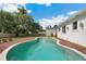 In-ground pool surrounded by a brick patio, lush greenery, and a wooden fence at 13917 8Th St, Dade City, FL 33525