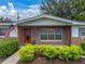 Charming porch and entry featuring brick accents, decorative columns, mature shrubbery, and an American flag at 140 Morrow Cir, Brandon, FL 33510