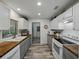 Well-lit galley kitchen with white cabinets, wooden countertops, and modern appliances at 140 Morrow Cir, Brandon, FL 33510