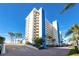 Modern condo building exterior with palm trees, a well maintained paved drive, and beautiful blue skies at 15000 Gulf Blvd # 407, Madeira Beach, FL 33708
