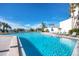 A beautiful blue swimming pool surrounded by palm trees and lounge chairs under a clear sky at 15000 Gulf Blvd # 407, Madeira Beach, FL 33708