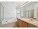 Well-lit main bathroom featuring a large mirror, dual sinks, tiled floor, and separate shower and bathtub at 15709 Leatherleaf Ln, Land O Lakes, FL 34638