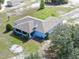 Aerial view of a single-story home with a screened-in porch, nestled among lush trees and greenery at 17023 Alderman Turner Rd, Wimauma, FL 33598