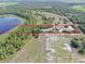 Aerial view of a property bordered in red, showcasing a home near a serene lake with lush greenery at 17023 Alderman Turner Rd, Wimauma, FL 33598