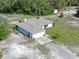 Aerial view of a blue single-story home with a long driveway, surrounded by lush greenery on a spacious lot at 17023 Alderman Turner Rd, Wimauma, FL 33598