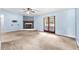 Open living room with neutral carpet, cozy fireplace, ceiling fan, and sliding door access to backyard at 17023 Alderman Turner Rd, Wimauma, FL 33598