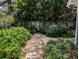 Backyard stone path with bench seat is surrounded by lush green tropical foliage at 210 Kingsway Dr, Temple Terrace, FL 33617