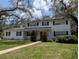 Charming two-story home with a manicured lawn, a red door and mature trees at 210 Kingsway Dr, Temple Terrace, FL 33617
