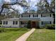 Charming two-story home with a manicured lawn, a red door and mature trees at 210 Kingsway Dr, Temple Terrace, FL 33617