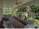 View of enclosed porch featuring brick flooring, ceiling fans, and striped chairs near lush foliage at 210 Kingsway Dr, Temple Terrace, FL 33617