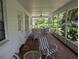 Enclosed brick porch with ceiling fan, white wicker furniture, and view to lush tropical foliage at 210 Kingsway Dr, Temple Terrace, FL 33617