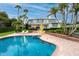A pristine pool, manicured lawn, dining area, and mature palm trees create a serene and inviting backyard oasis at 224 Harbor View Ln, Largo, FL 33770
