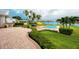 Lush backyard with a pool, canal view, built-in grill, manicured lawn, and vibrant landscaping at 224 Harbor View Ln, Largo, FL 33770