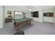 Well-lit game room with a pool table, a mounted TV, and backyard views from a window at 224 Harbor View Ln, Largo, FL 33770