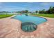 Unique kidney-shaped pool and built in hot tub with brick accents offer a luxurious and relaxing outdoor space at 224 Harbor View Ln, Largo, FL 33770